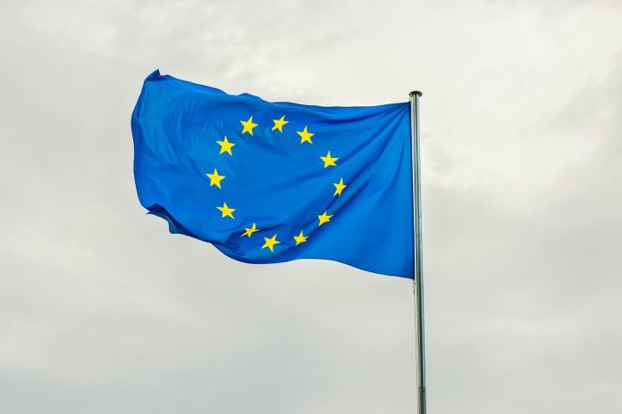Brüsszeli megállapodás: fiskális hatás — The European Union flag gracefully waving on a flagpole against a cloudy sky in