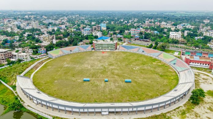 Stadion-beruházások: befektetői aggályok — Aerial view of an empty football stadium surrounded by a bustling cityscape.