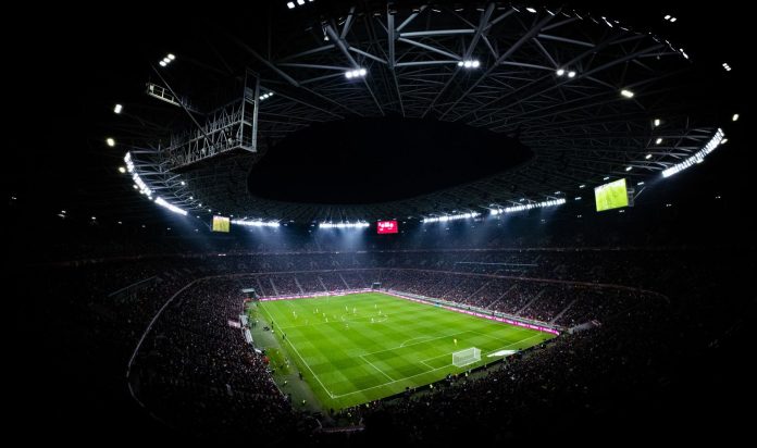 Klubpénzügyek: transzparencia-szempontok — Aerial view of a night football match in Budapest. Illuminated stadium full of f