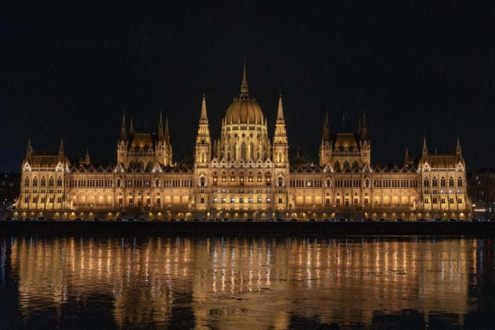 Sportklub-tulajdonlás: új szabályozási környezet — Captivating night view of the illuminated Hungarian Parliament Building reflecti