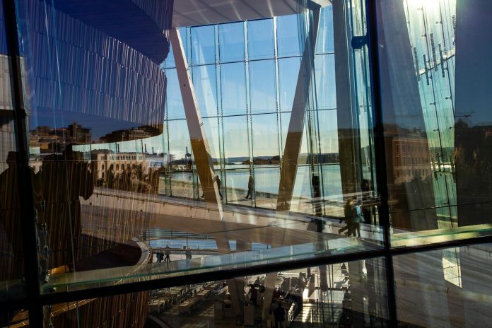 Színház-, film-, művészetfinanszírozás: fiskális hatás — Abstract view through glass of Oslo Opera House with reflections and cityscape.