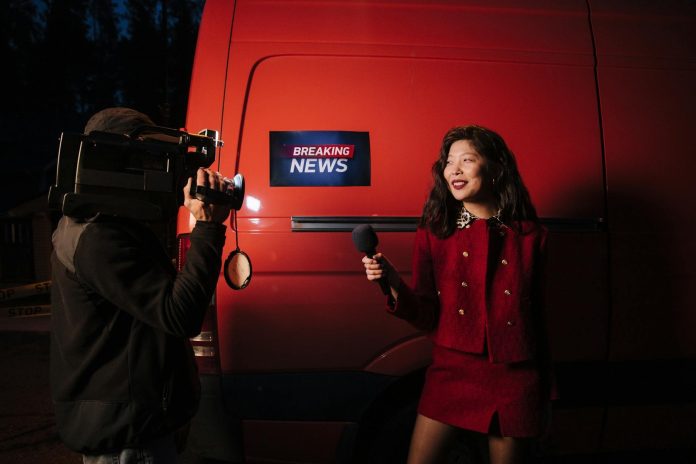 Vizuális magyarázó: törvényi háttér — Dynamic news reporter holding microphone near red van during nighttime outdoor b