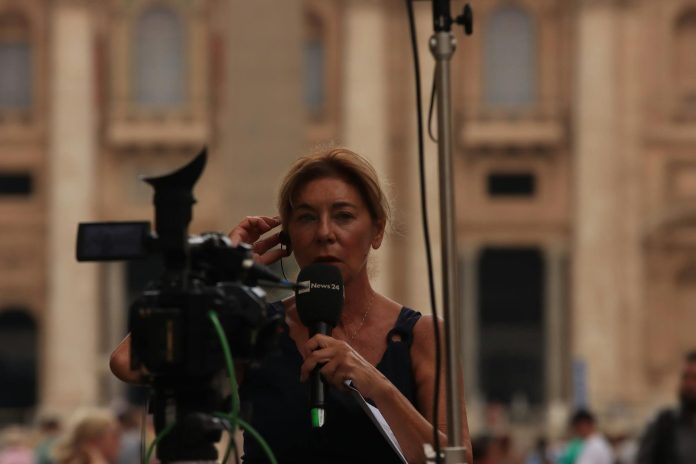 Videó riport: publikus források áttekintése — Journalist reporting live from Vatican City, capturing the essence of urban broa