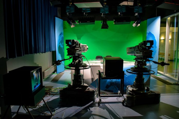Podcast: Visegrádi összehasonlítás — A TV studio setup featuring cameras and a green screen for production purposes.