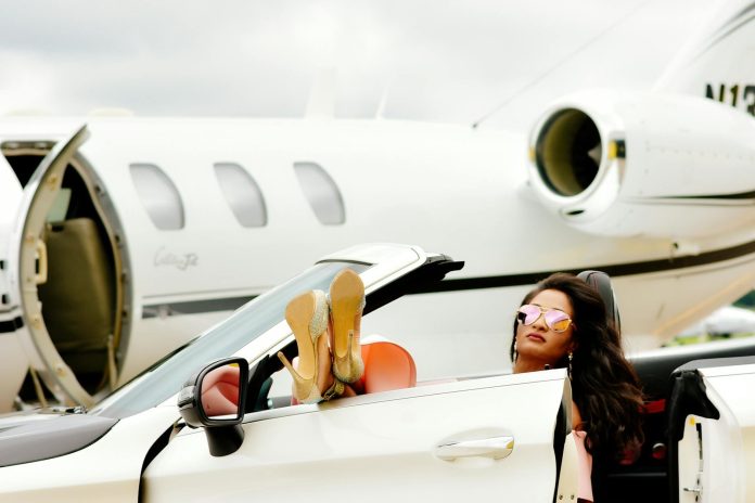 Nagyvállalkozók: 2026-os trendek és kilátások — Luxurious travel scene with a woman in a convertible beside a private jet.