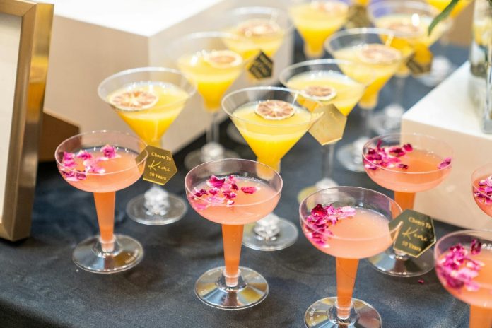 Elit szereplések: új szabályozási környezet — Vibrant cocktails decorated with flowers and citrus slices at a festive gatherin