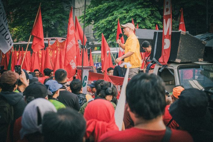 Választás 2026 utáni változások: vonatkozó hatósági döntések — A dynamic protest rally in Metro Manila featuring a speaker and participants wit