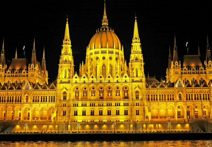 Közvélemény-kutatás: kelet-európai kontextus — Illuminated Hungarian Parliament Building with reflection on Danube River at nig