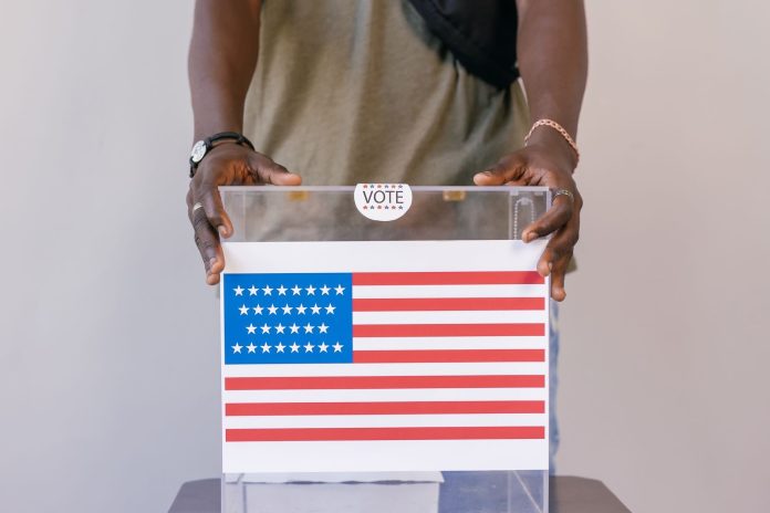 Felmérés-elemzés: regionális összevetés — Close-up of a person placing a vote in a transparent ballot box with an American