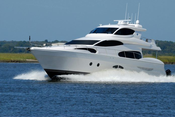 NER életstílus: vagyonnyilatkozati háttér — A modern luxury yacht cruising swiftly on a calm river under a clear blue sky.