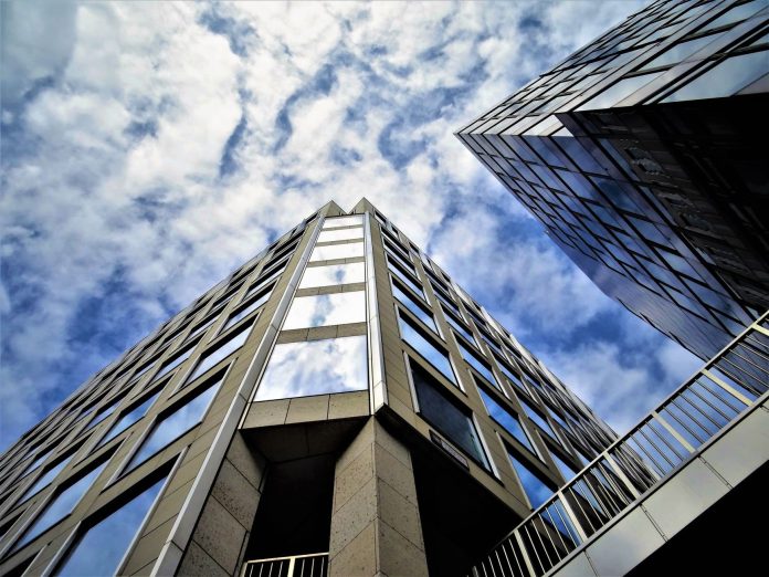 Állami beruházás-elemzés: K-Monitor adatok tükrében a magyar piacon — Low angle view of modern skyscraper with glass facade reflecting the sky.