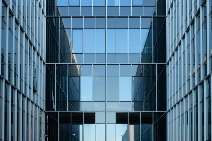 Építőipari közbeszerzés monitor: EU-szabályozói feltételek — Contemporary building facade with reflective glass windows in an urban environme