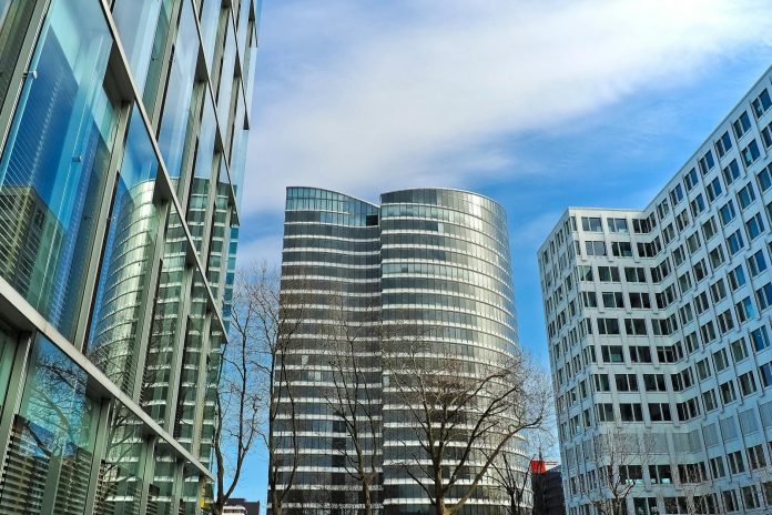 Állami beruházás-elemzés: új szabályozási környezet a magyar piacon — A striking view of modern skyscrapers against a clear blue sky, showcasing conte
