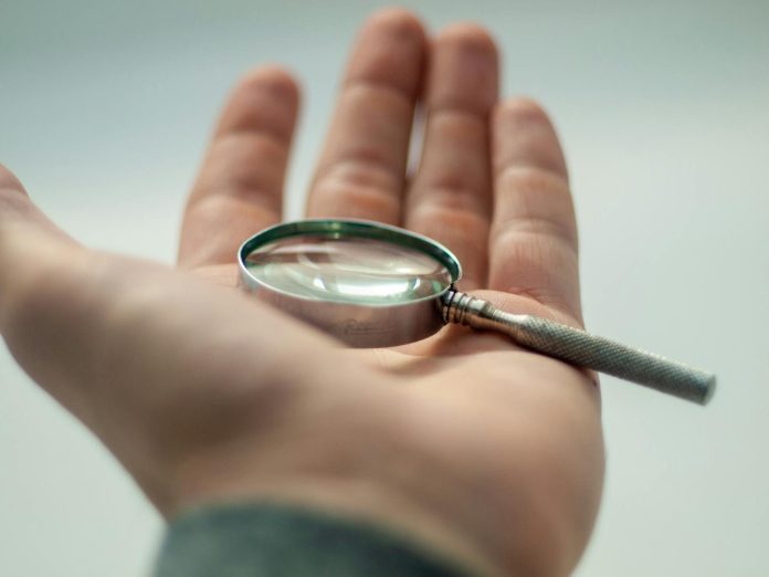 Market Építő Zrt. (Garancsi István) — A detailed close-up of a hand holding a magnifying glass, showcasing precision a