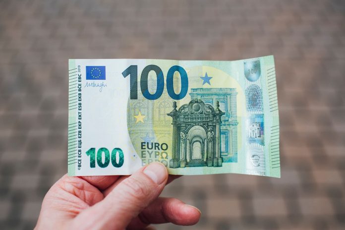EU-források feloldása — 34 milliárd EUR várható (Brüsszeli megállapodás 2026-05-25) — Close-up photo showing a person holding a 100 euro banknote agai