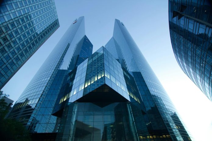Aero Vodochody / SI 13 Aero — MOL Hernádi Zsolt — Low-angle view of modern glass skyscrapers reflecting a clear blue sky. Perfect