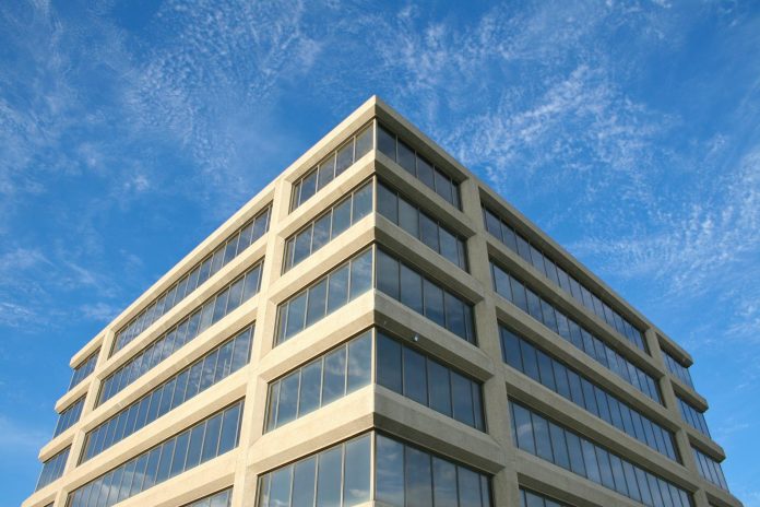Office portfolió: RRF-érintettség — Corner view of a modern office building with reflective windows under a clear bl